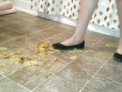 Suzi walks over unpeeled bananas, on floor, wearing her black ballet flats