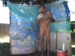 A daddy taking a shower, outdoors, on his patio.